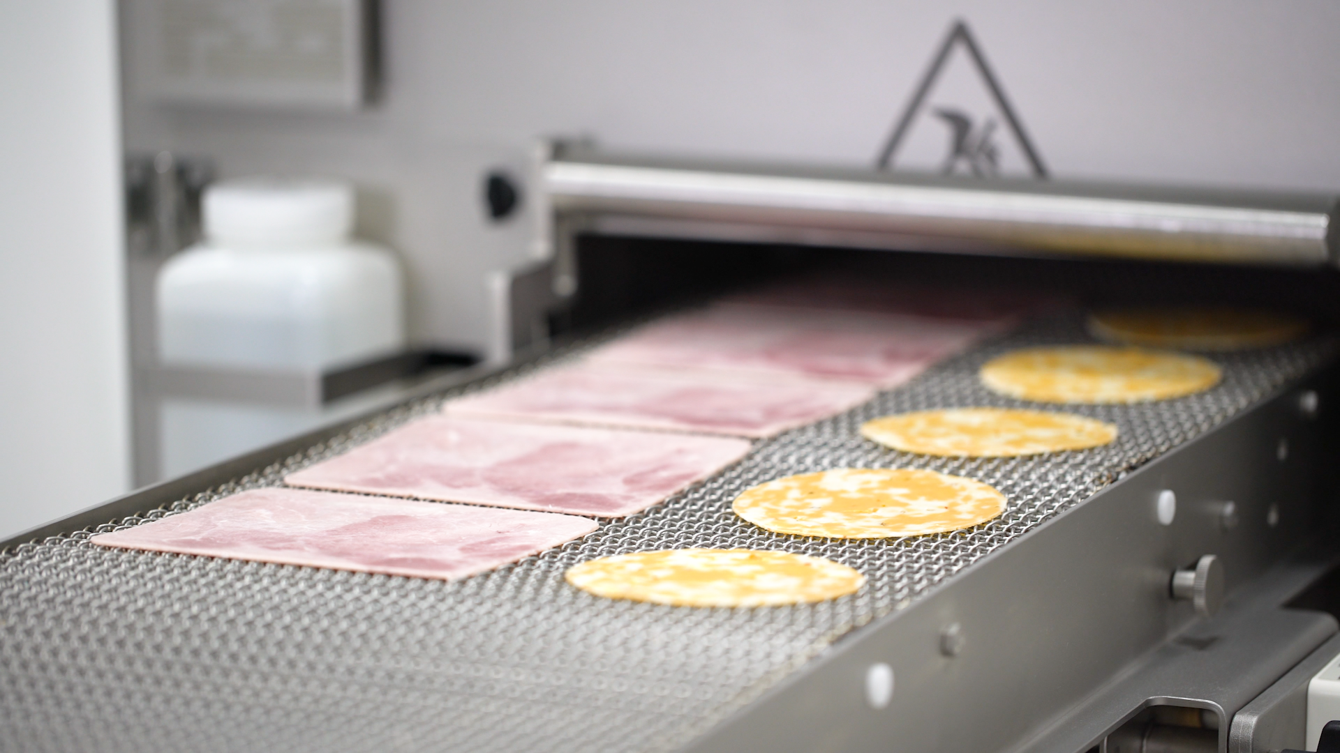 Round cheese slices on a Grote Company industrial cheese slicer.